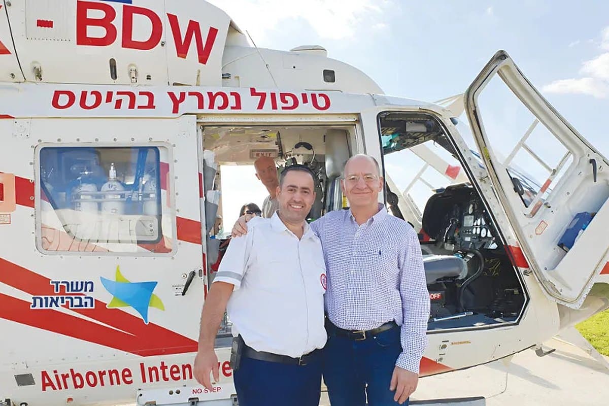 An MDA paramedic and Dr. Michael Block smile beside an open Magen David Adom airborne intensive care helicopter